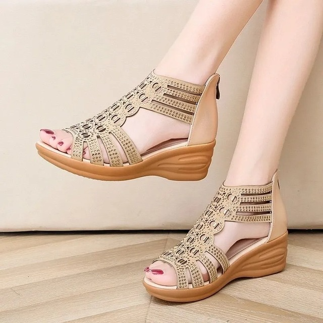 Close-up of elegant beige wedge sandals worn by a model against a neutral background.