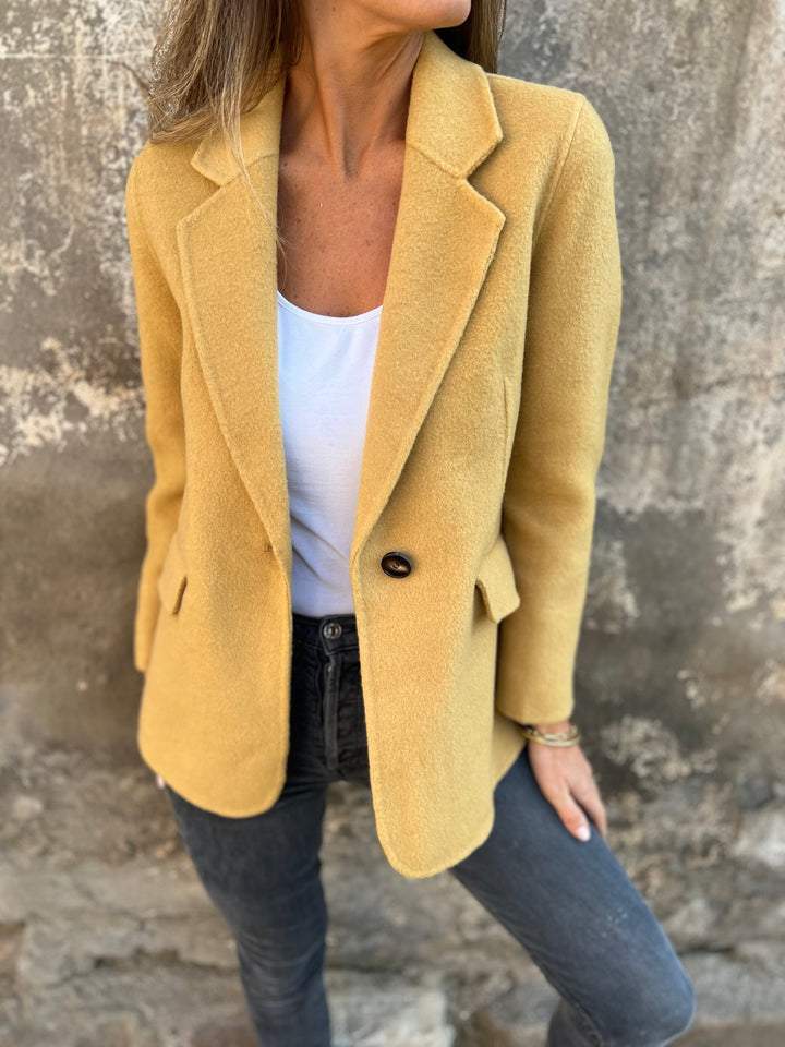 Close-up of fabric texture and button detail on women's tailored jacket