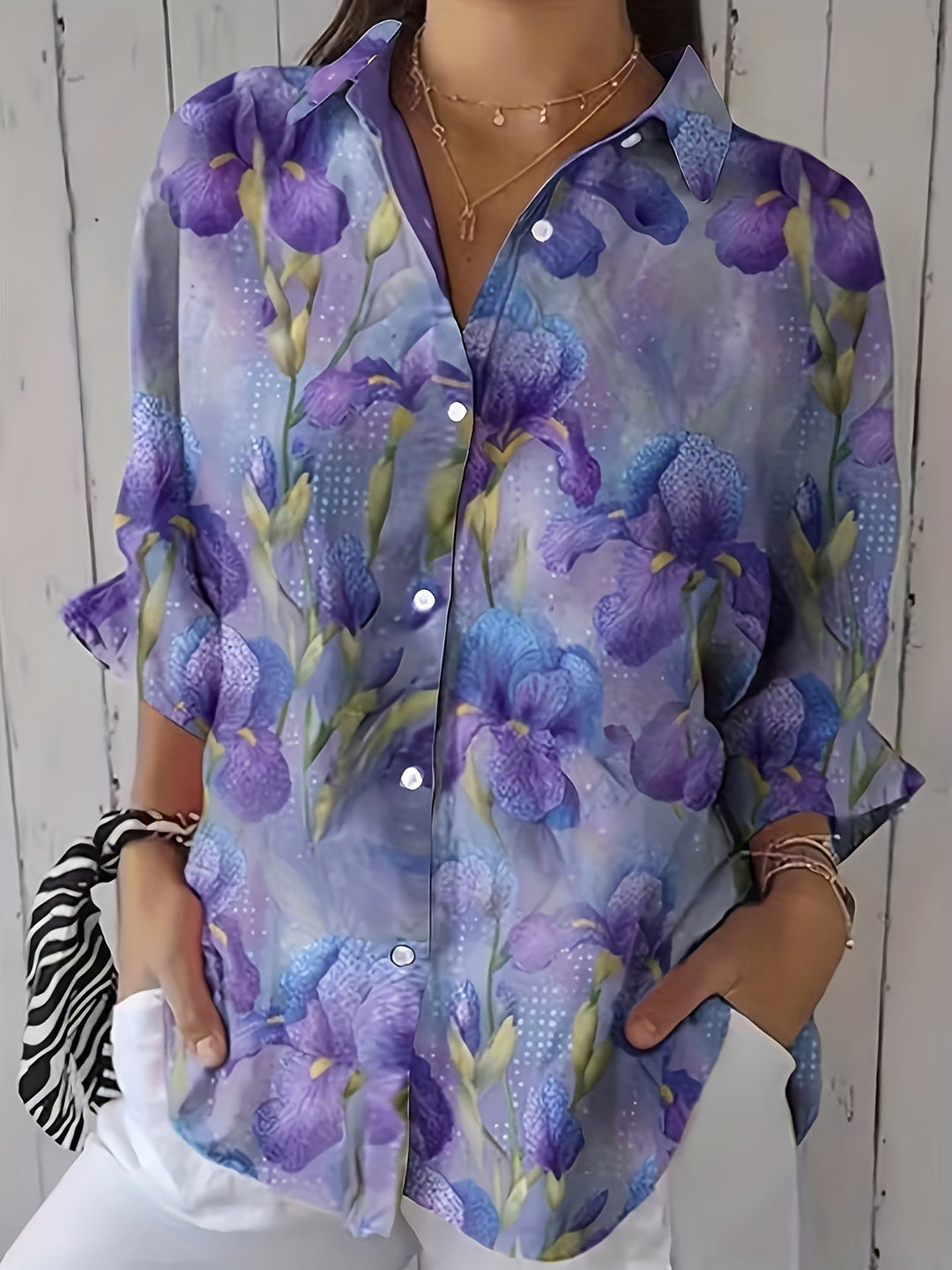 Woman wearing a purple floral button-up blouse with white trousers