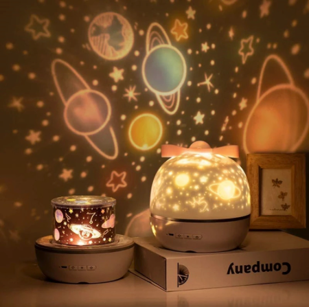 StarGaze Projector projecting a colorful galaxy and stars onto a bedroom wall next to a book