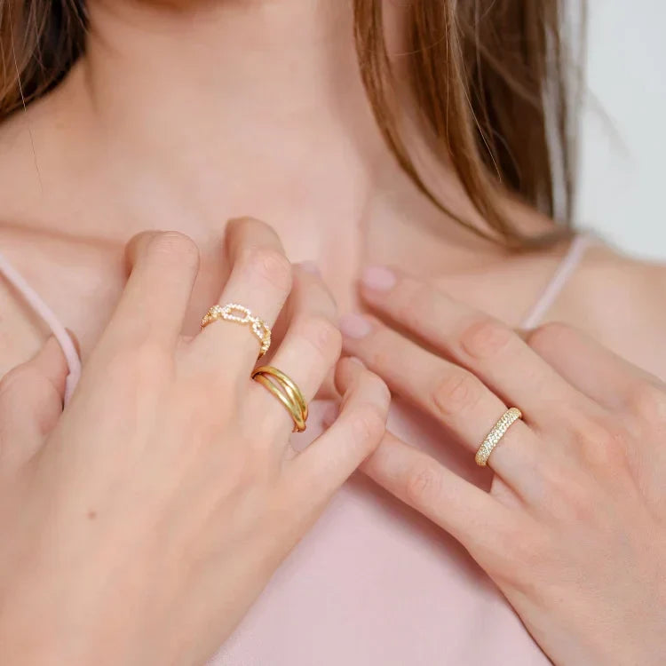 Close-up of a woman wearing a gold link ring with zirconia stones alongside other stacking rings