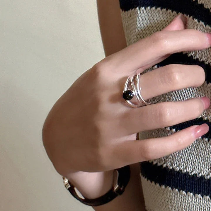 Close-up of womens silver statement ring featuring multiple lines and colorful gemstones