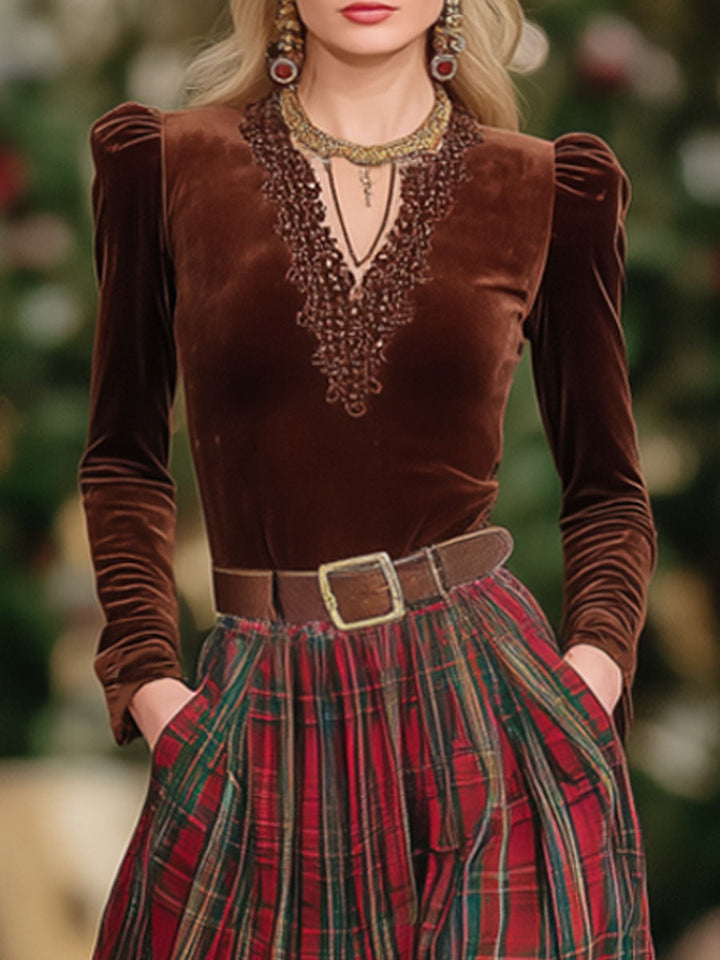 Close-up of a woman wearing a brown V-neck top with detailed neckline and red plaid skirt.