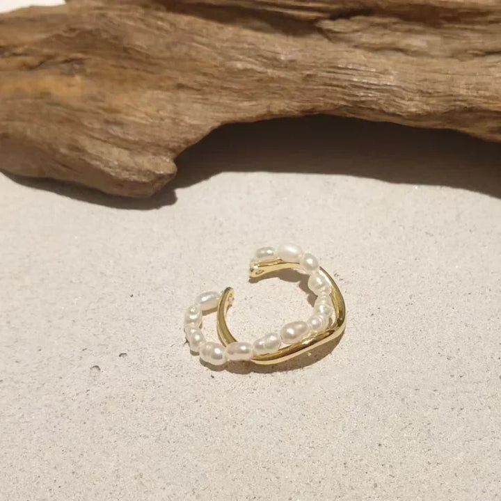 Gold pearl ring displayed next to natural wood decor