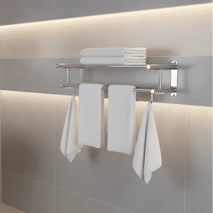 Wall mounted stainless steel towel rail holding white folded towels and hanging washcloths in a modern bathroom