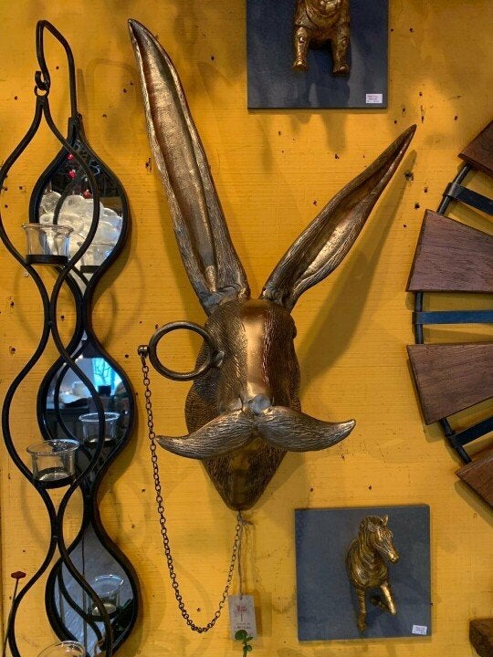 Close-up of a whimsical rabbit wall sculpture wearing spectacles and a bowtie against a yellow wall