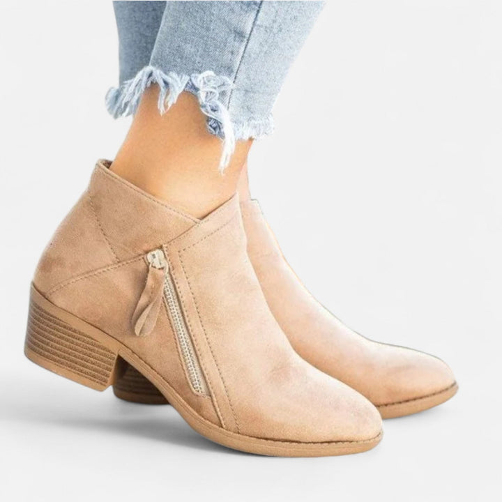 Close-up view of beige block heel ankle boots with side zipper detail