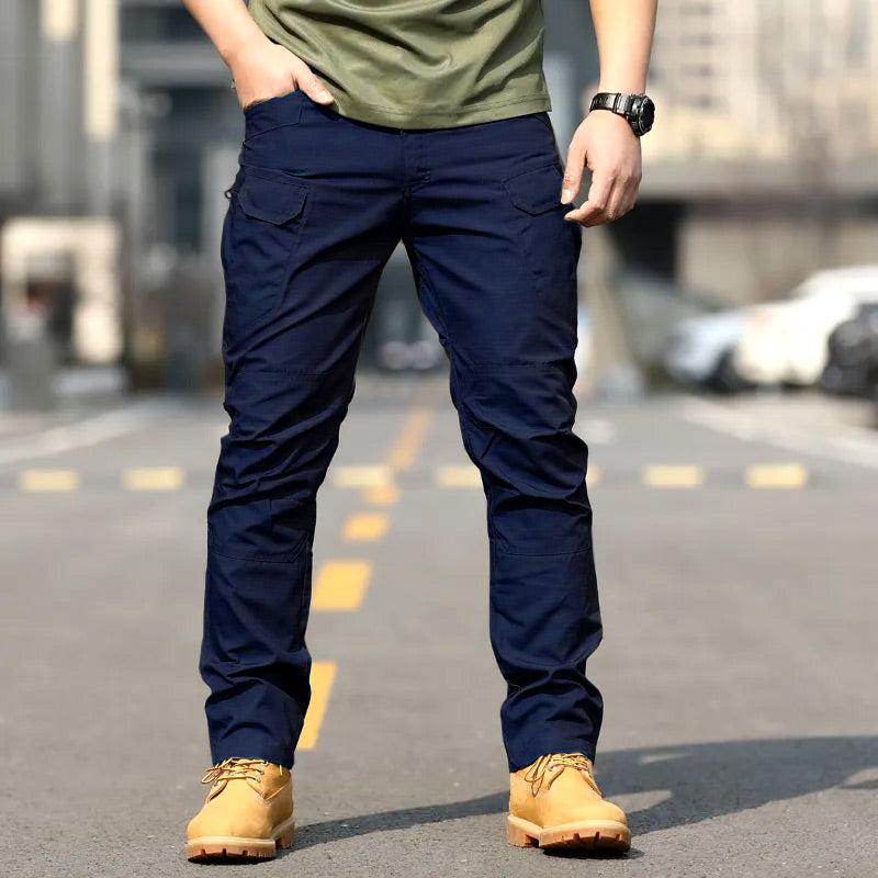 Folded stack of blue, black, and green waterproof tactical trousers