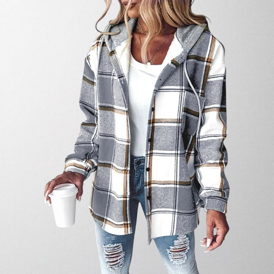 Woman wearing a grey plaid hooded jacket with a relaxed fit holding a coffee cup