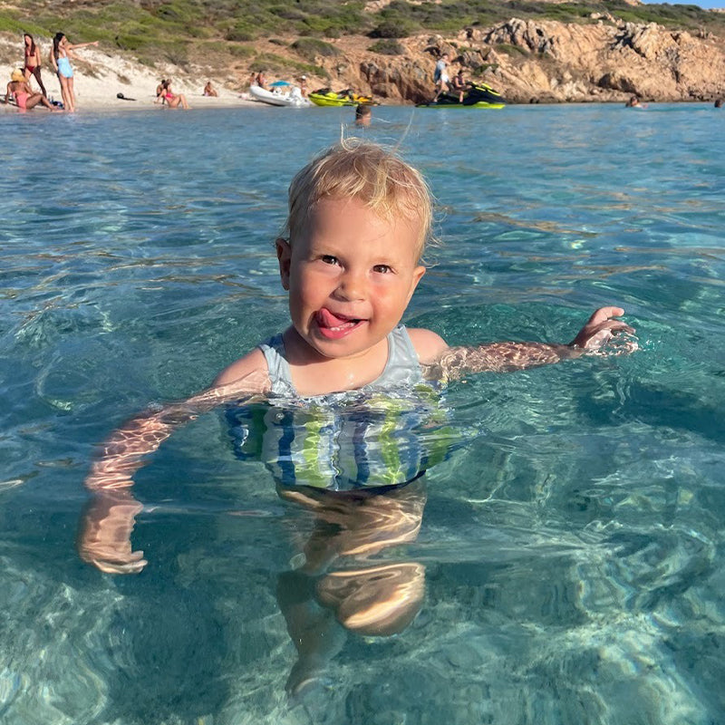 Active toddler running near pool in float jacket