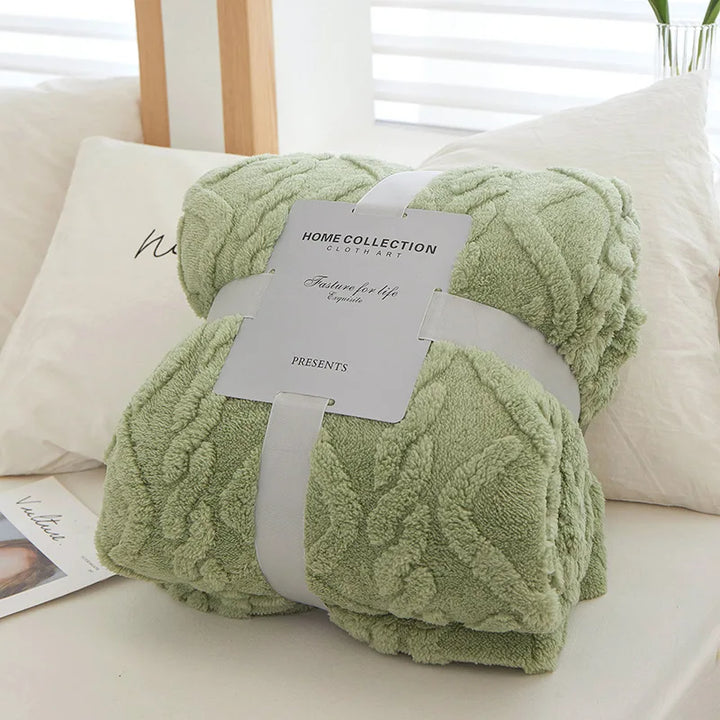 Folded green bedroom blanket packaged with decorative band on a bed