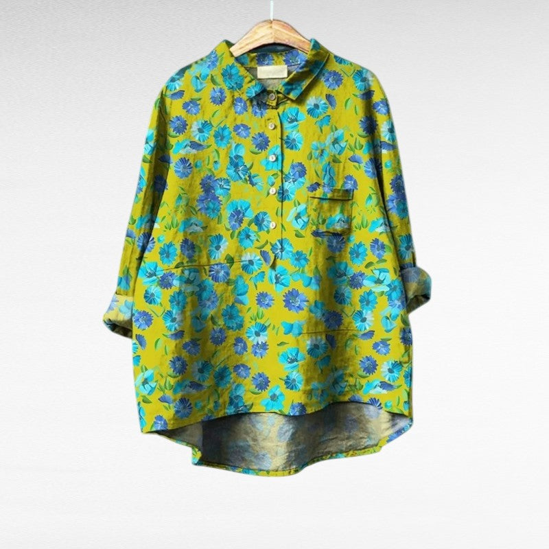 Green floral summer blouse for women hanging against a white background
