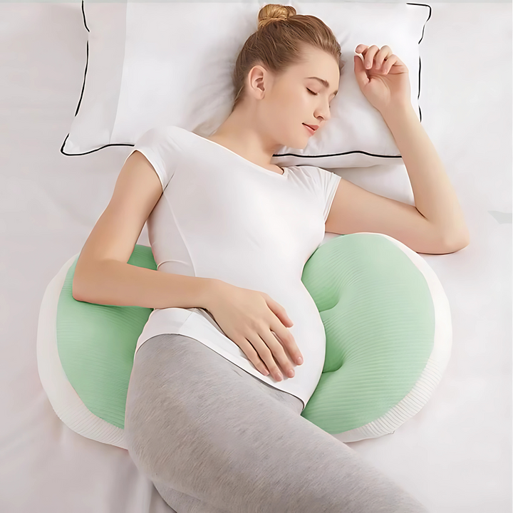 Pregnant woman sleeping comfortably on her side using a green and white maternity butterfly support pillow