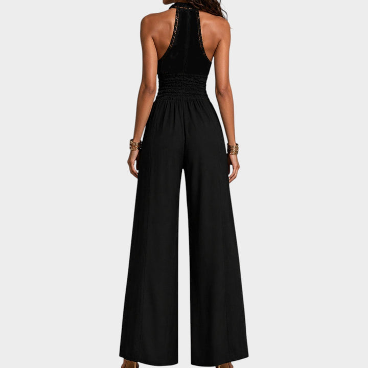 Back view of a woman wearing a black wide-leg jumpsuit with halter neck styling