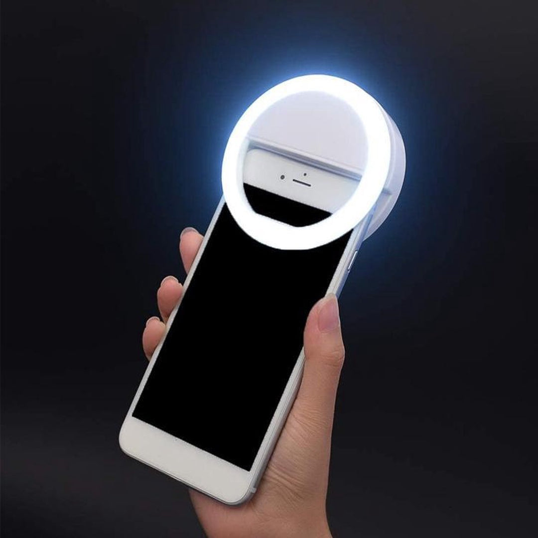 Portable selfie ring light clipped onto a smartphone held in hand