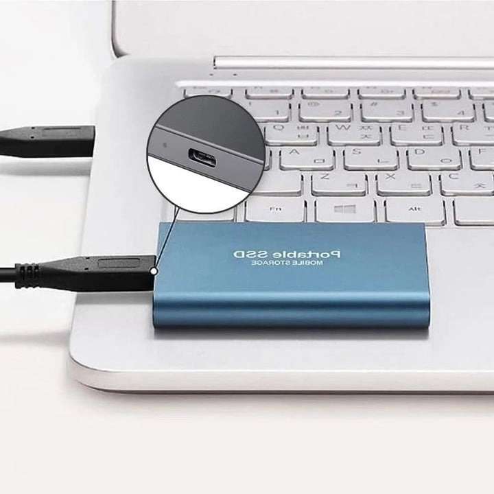Blue portable SSD connected to a laptop keyboard via USB cable