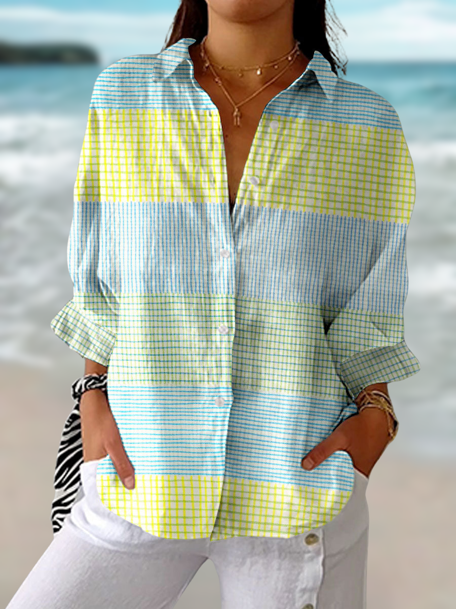 Woman wearing a pastel grid button-down blouse with long sleeves standing outdoors near the beach.