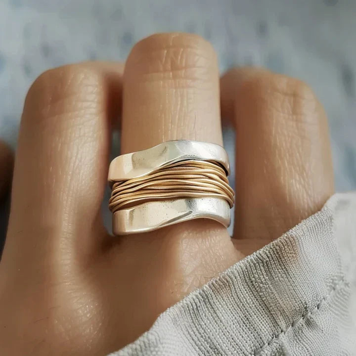 Women's two-tone statement ring worn on finger, showcasing silver and gold details