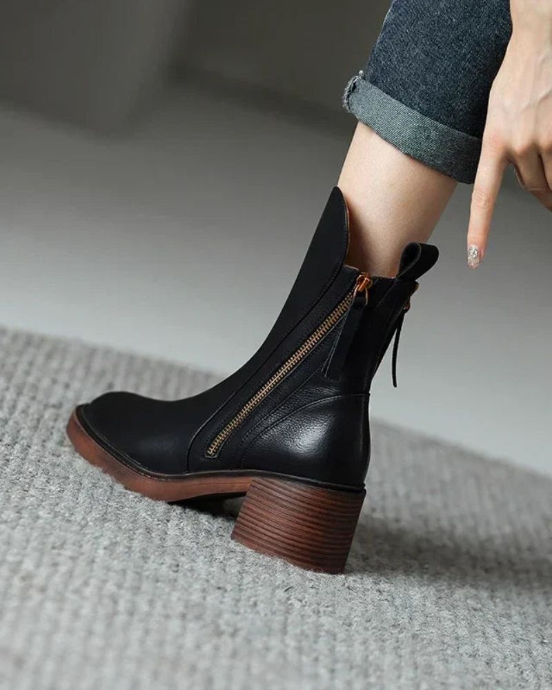 Close-up of black block heel boot worn with jeans, showing side zipper detail