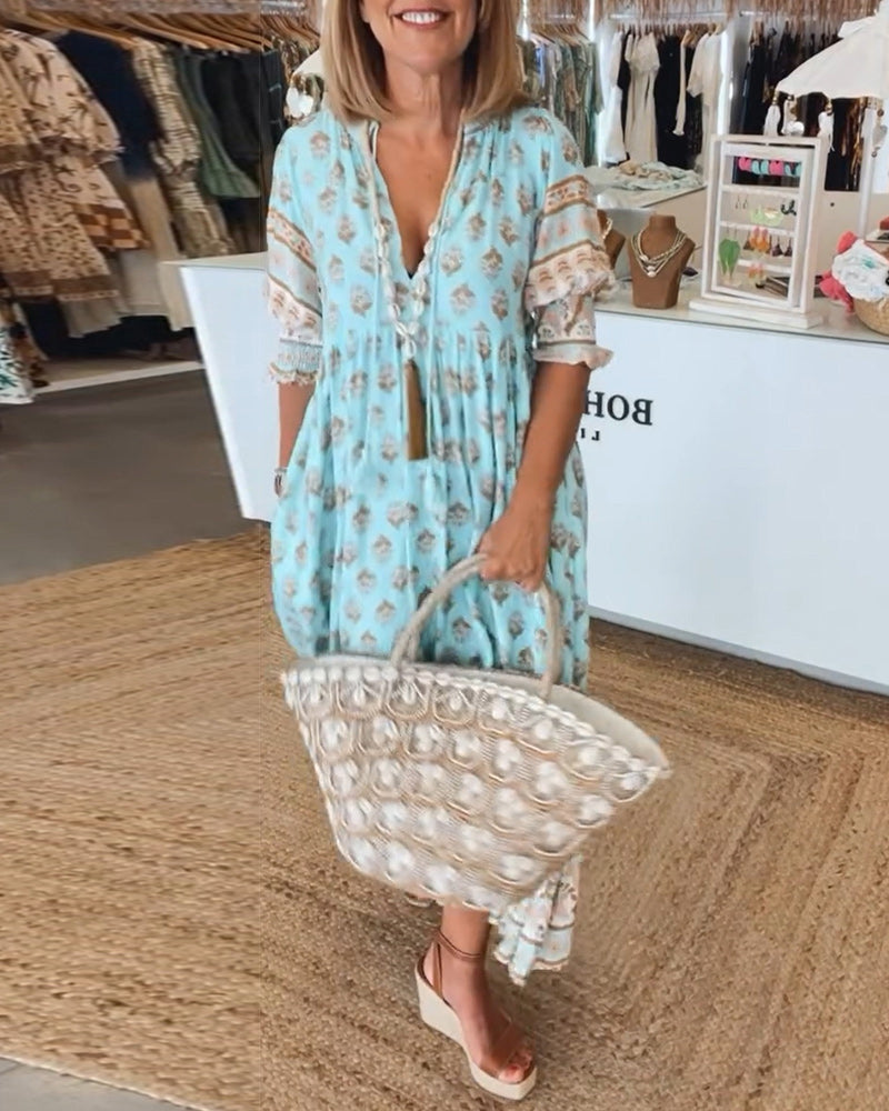 Model wearing blue Verona printed V-neck half-sleeve dress holding a woven bag