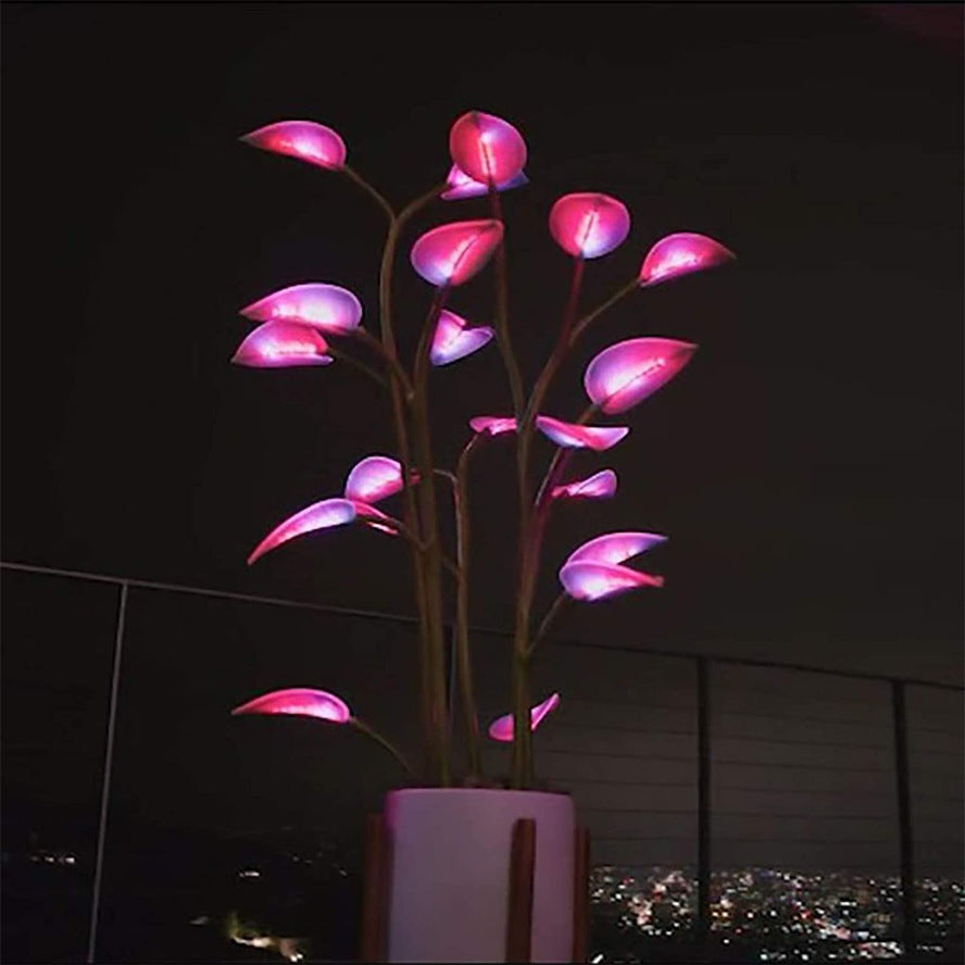 Close-up of the indoor LED plant glowing with vibrant pink ambient light in a dark room.
