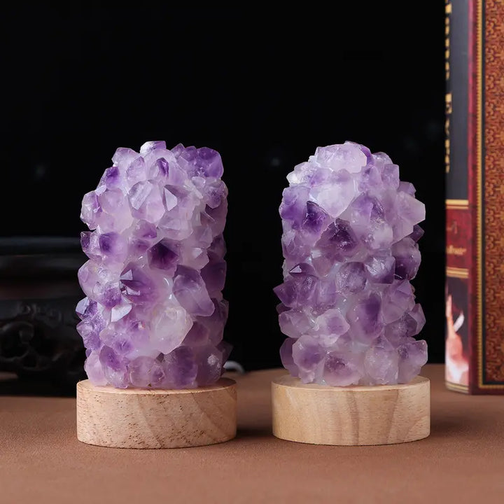 Two raw amethyst crystal lamps displayed on wooden bases against a dark background