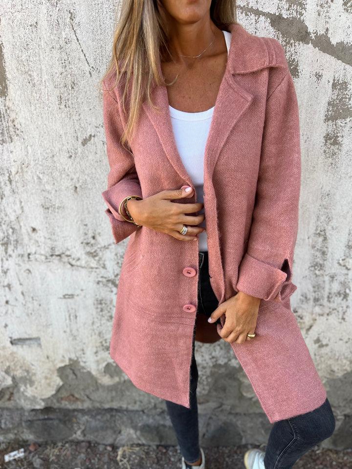 Close-up of a stylish pink long knit coat with lapel collar
