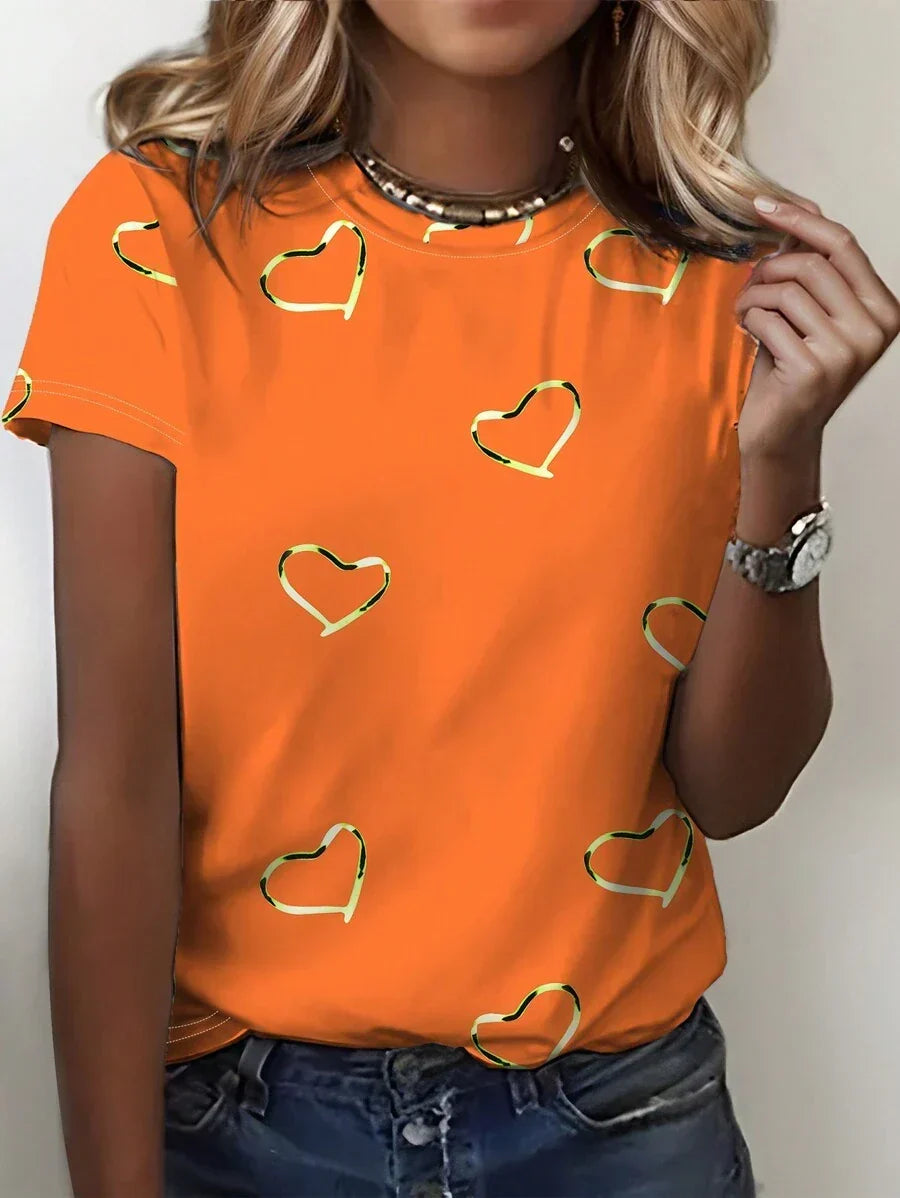 Front view of a woman wearing an orange heart print short-sleeve t-shirt with a necklace and a watch.