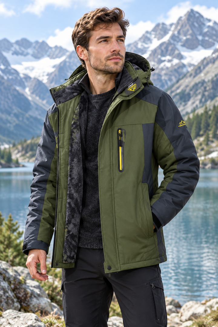 Man wearing green hooded outdoor jacket with dark trousers against mountain lake background
