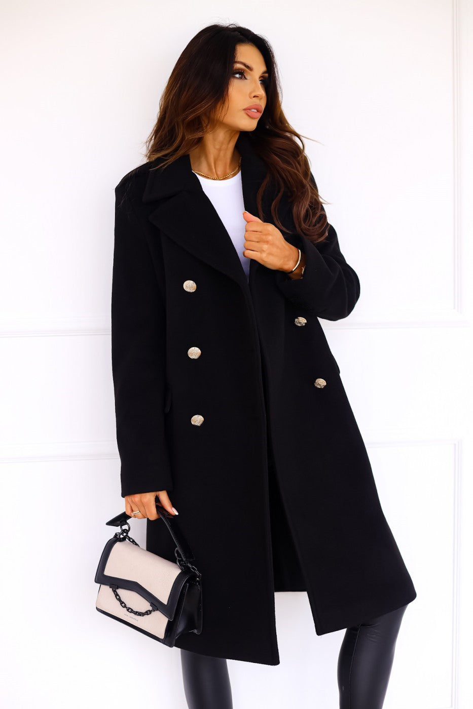 Close-up of a woman wearing a black double-breasted long coat with gold buttons