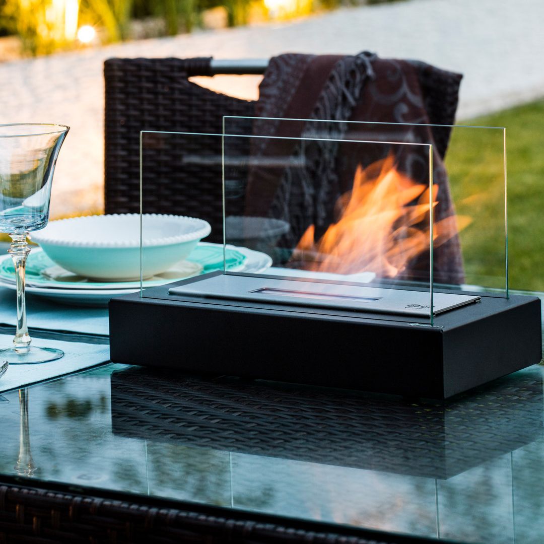 Black FireGlow tabletop bio-ethanol fireplace set up on an outdoor patio dining table
