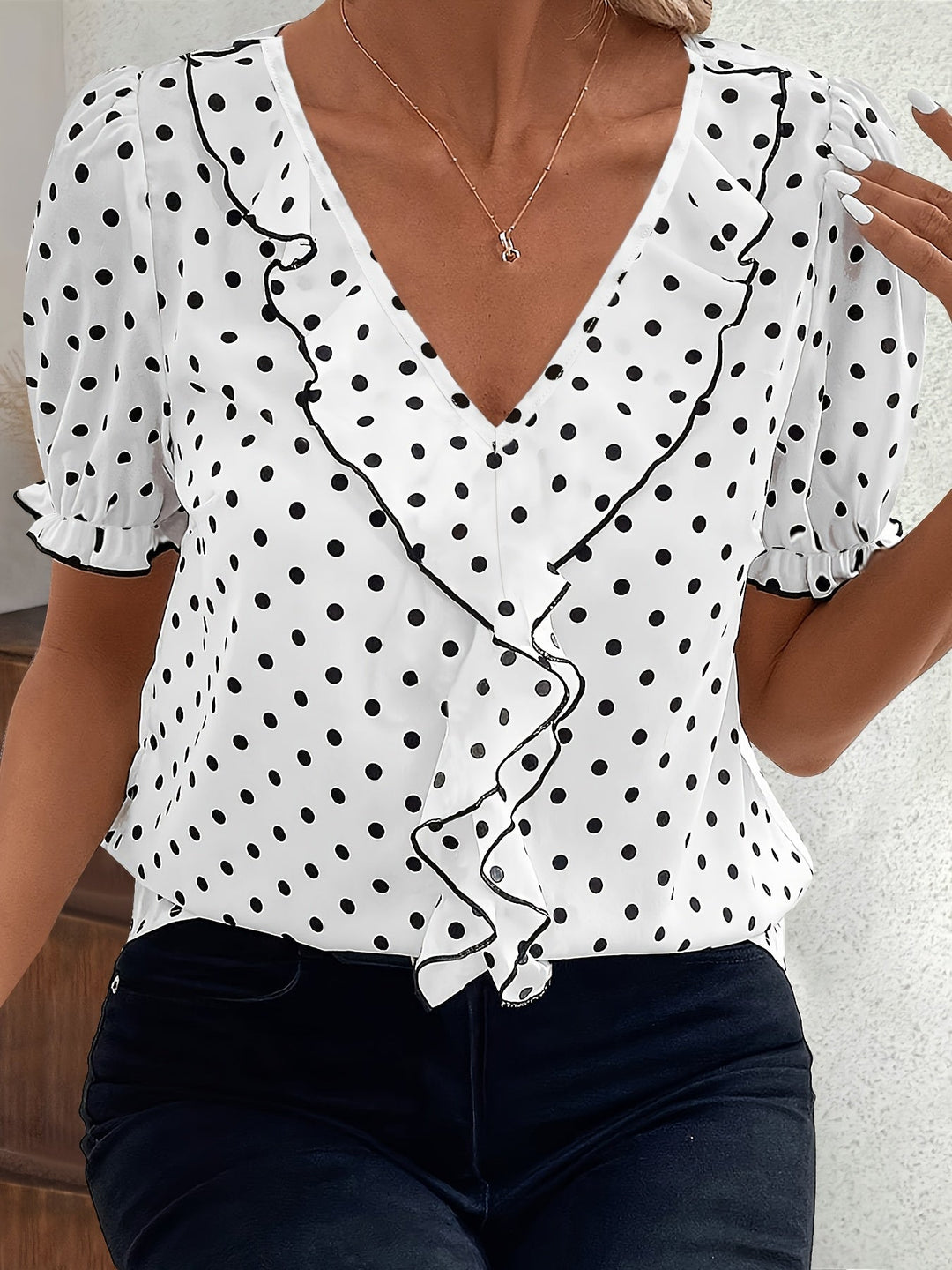 Woman wearing a white short sleeve bubble sleeve blouse with dark polka dots and V-neckline