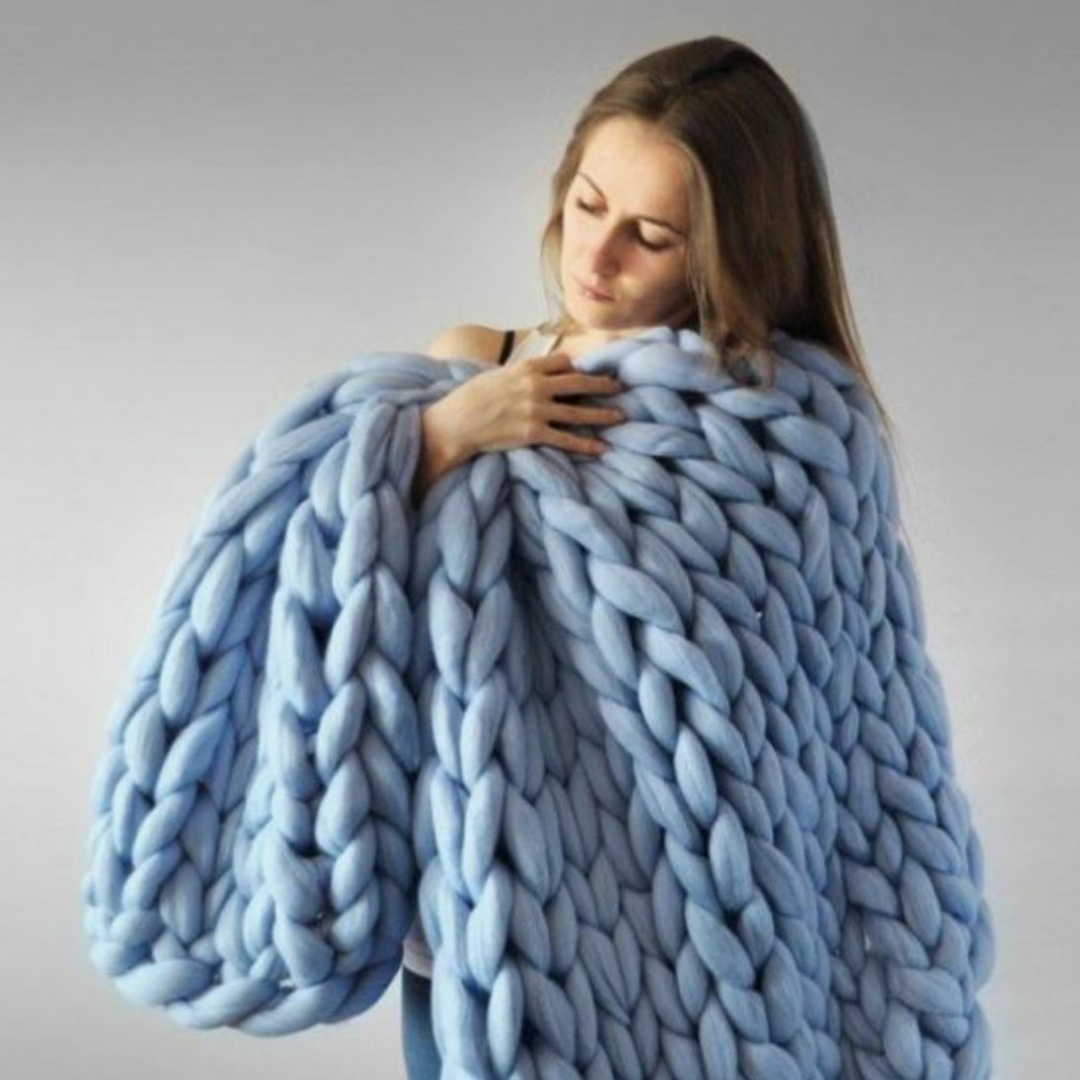 Hands gently touching the plush texture of a finished chunky knit blanket