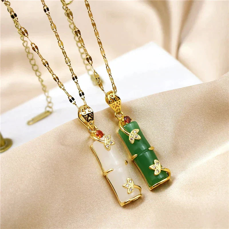 Green and white jade amulet necklaces displayed together on fabric