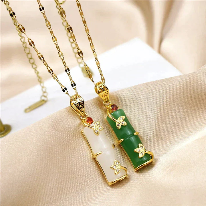 Green and white jade amulet necklaces displayed together on fabric