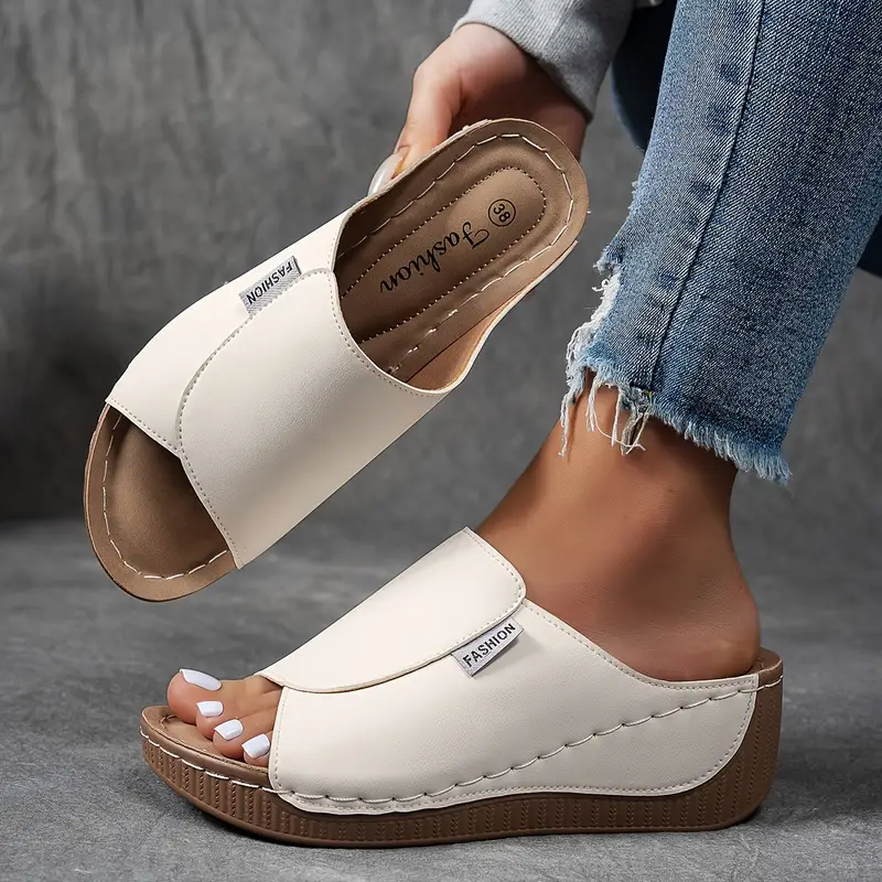 White orthopedic arch support wedge sandals displayed by hand against a dark background