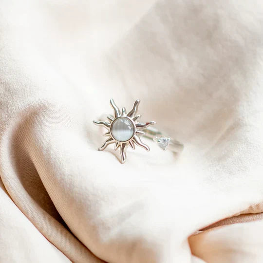 Close-up of a sterling silver sun spinner ring resting on soft neutral fabric