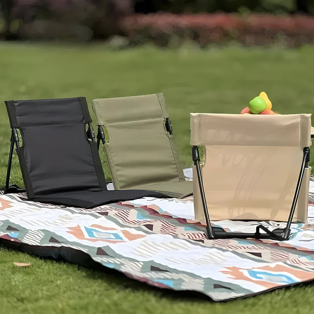 Three foldable camping chairs in black, army green, and beige displayed on a patterned picnic blanket outdoors.