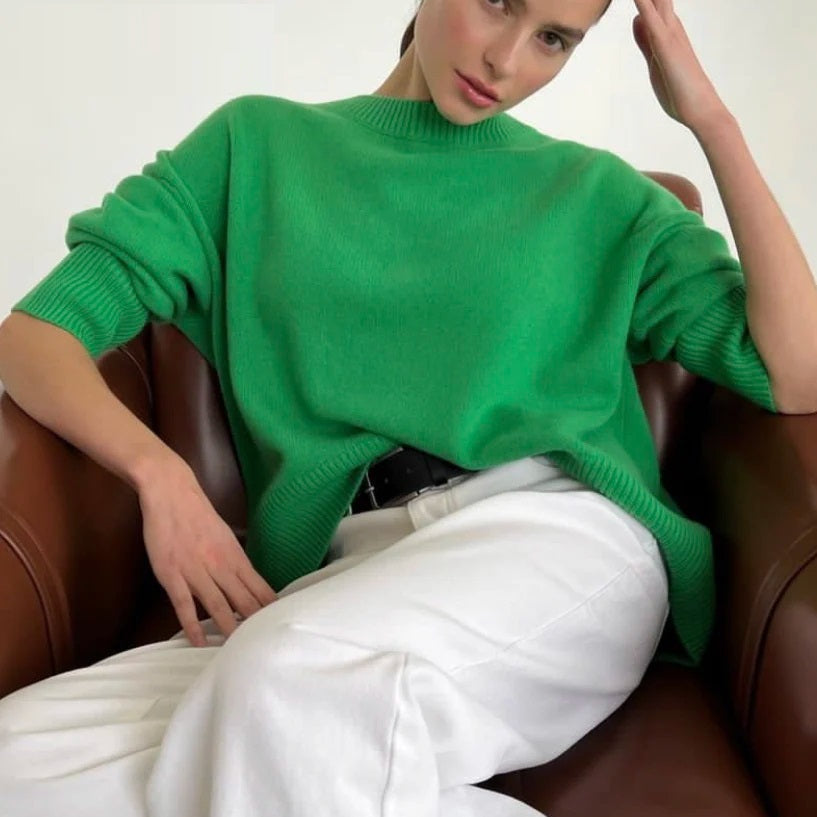 Woman wearing a bright green oversized knit jumper seated in a leather chair