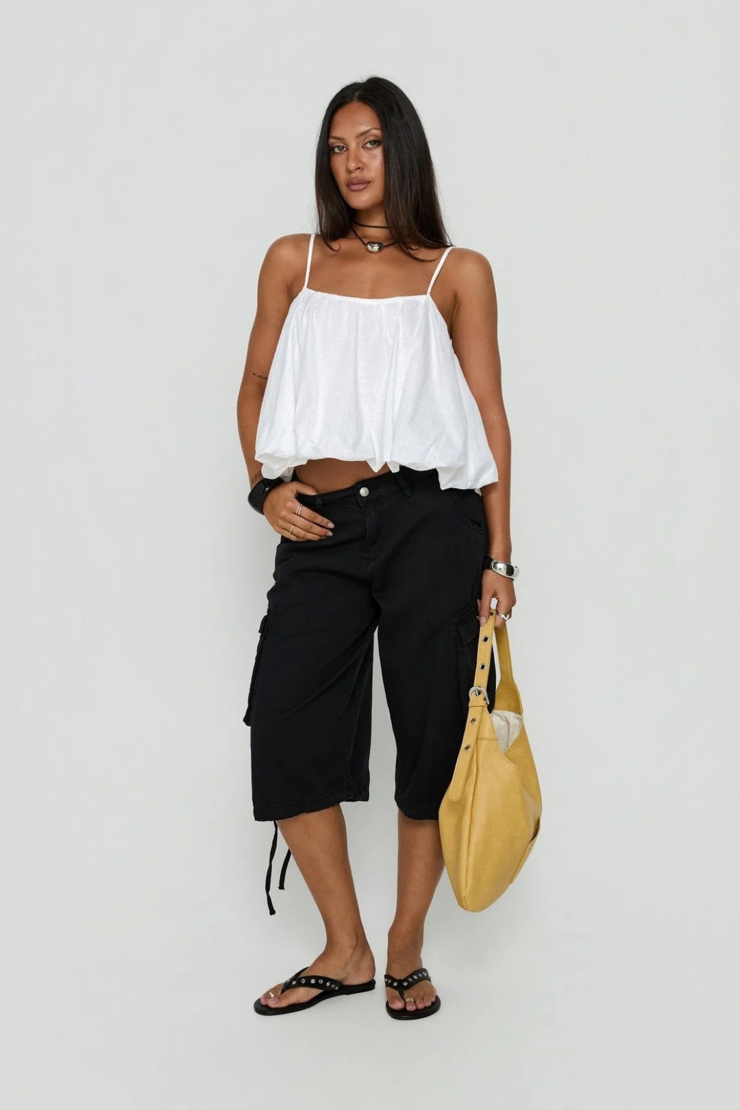 Model wearing women's black cargo utility shorts with a white top and yellow handbag
