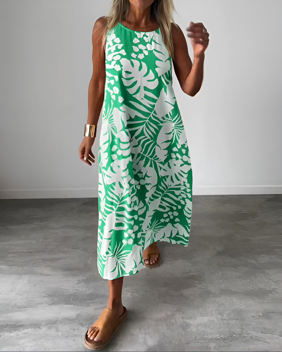 Woman wearing the Audrey elegant sleeveless dress in green with botanical print