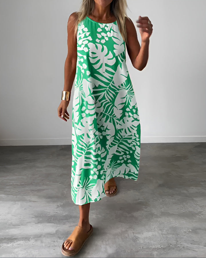 Woman wearing the Audrey elegant sleeveless dress in green with botanical print