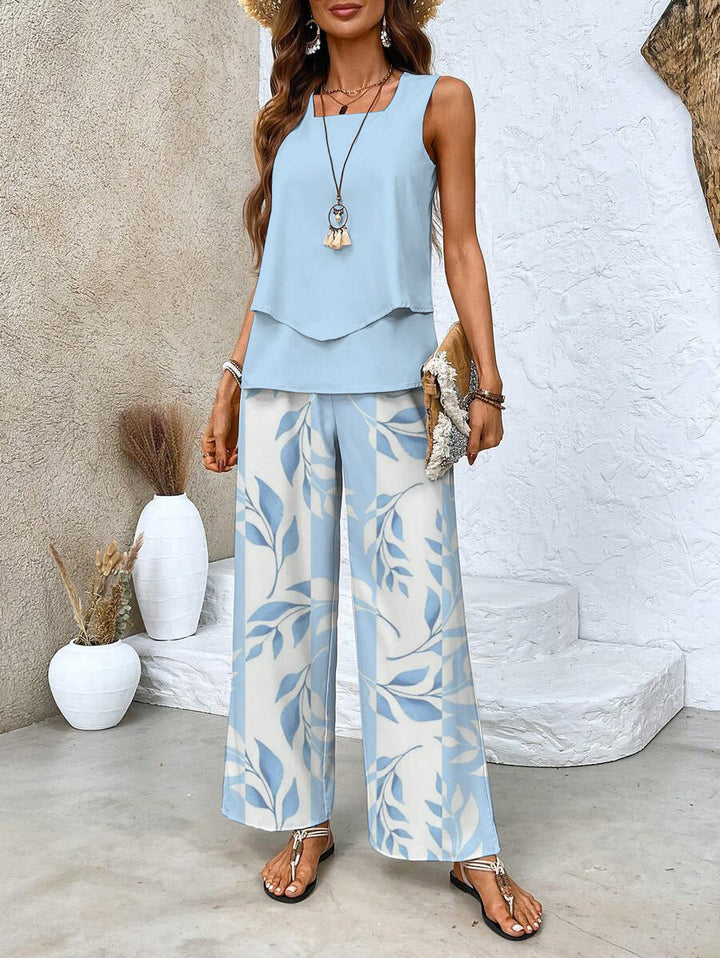 Front view of a woman wearing a light blue summer two-piece outfit with leaf-patterned trousers