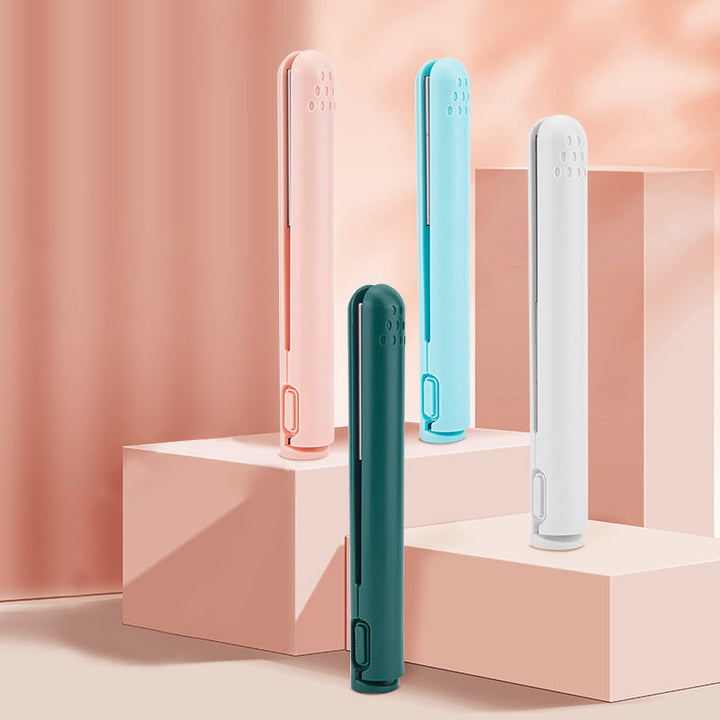 Mini curling and straightening irons displayed in pink, blue, white, and green on a pink surface
