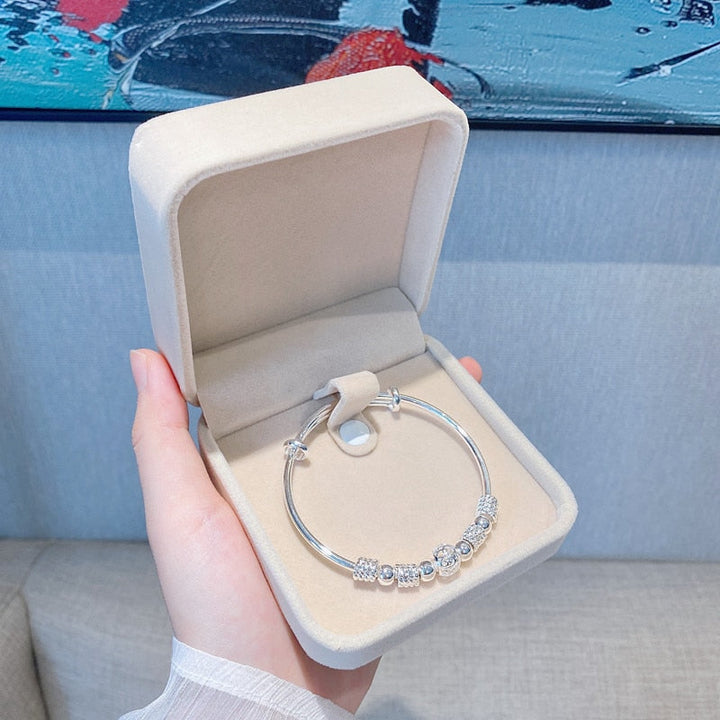Silver lucky beads charm bracelet presented in an open beige gift box