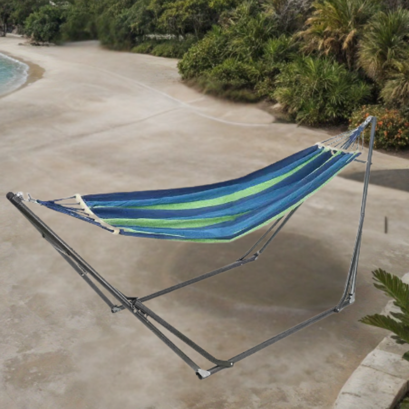 Padded blue and green hammock set up outdoors on a patio with a metal stand