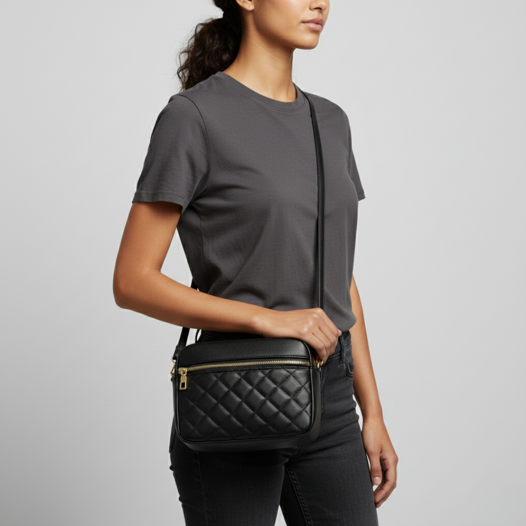 Model wearing black quilted crossbody bag against grey background