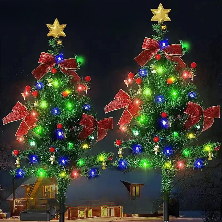 Two illuminated solar Christmas tree garden lights outdoors at night