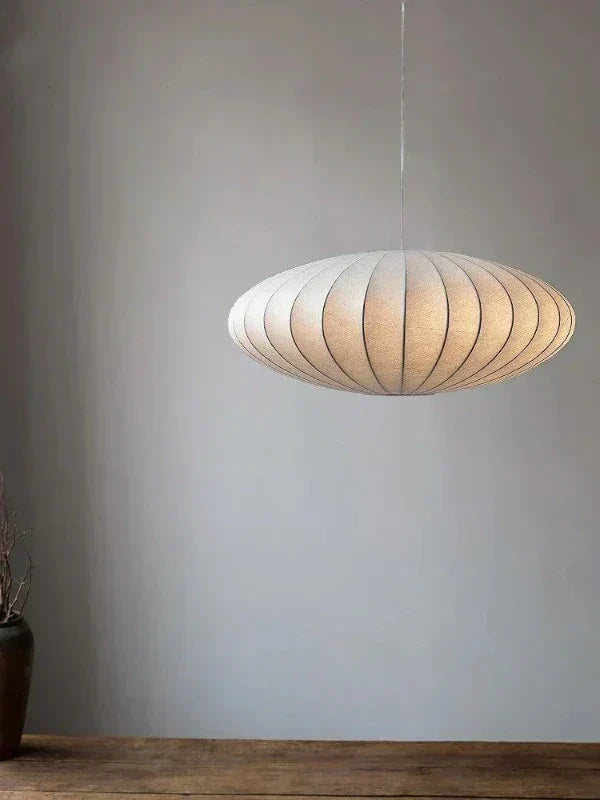 Silk pendant lamp hanging above a wooden table in a minimalist room
