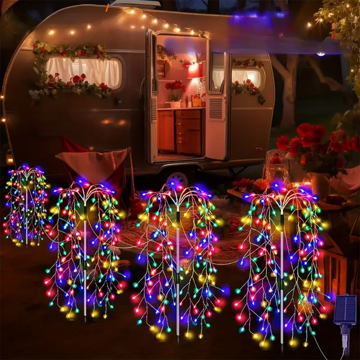 Outdoor camper trailer decorated with glowing multicolored solar firework string lights at night